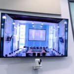 Bright, modern conference room with large screen, high-tech equipment for virtual meetings.